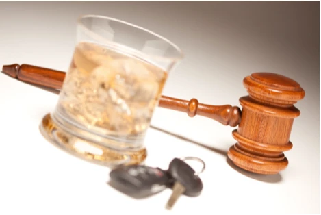A glass of alcohol next to keys and a gavel.