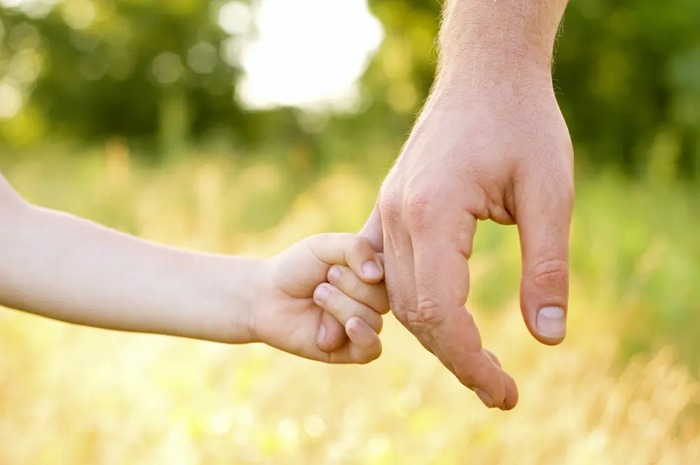 A child holding his dad's hand.