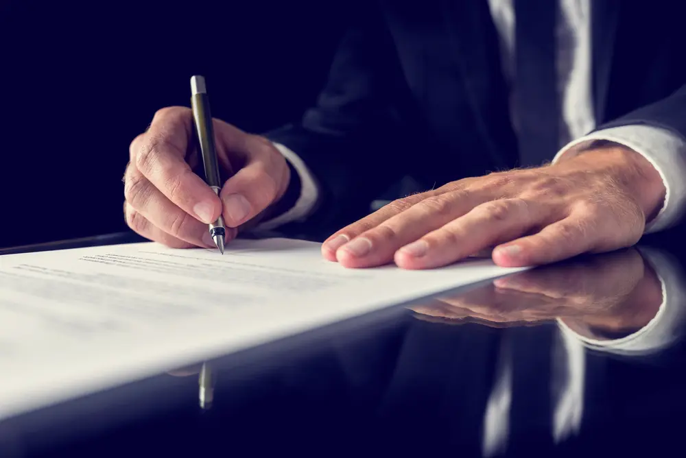 A male attorney signing documents.