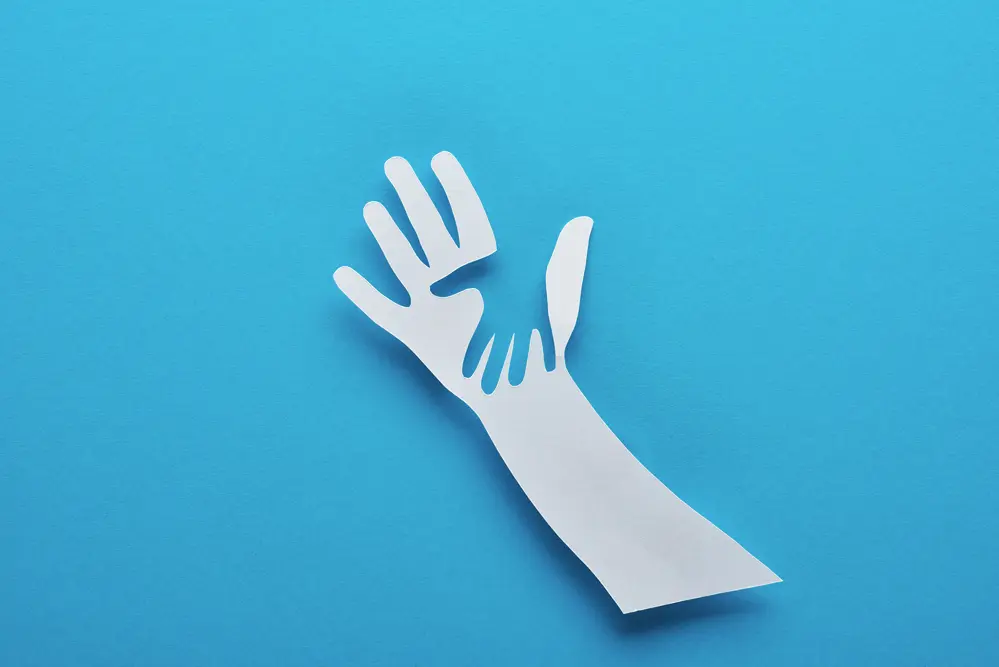 A paper cutout of a hand with a childs hand.