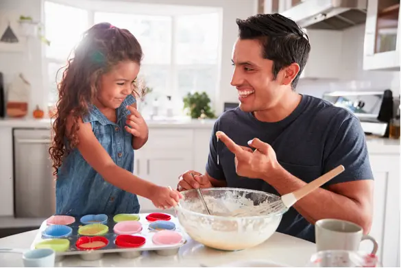 A father baking cupcakes with his daughter.
