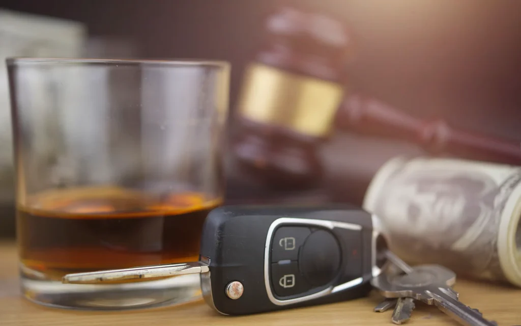Judge gavel, glass of alcohol, roll of money, and car keys representing a DUI. If you've been charged with a DUI in Oklahoma City, contact our DUI lawyers today.