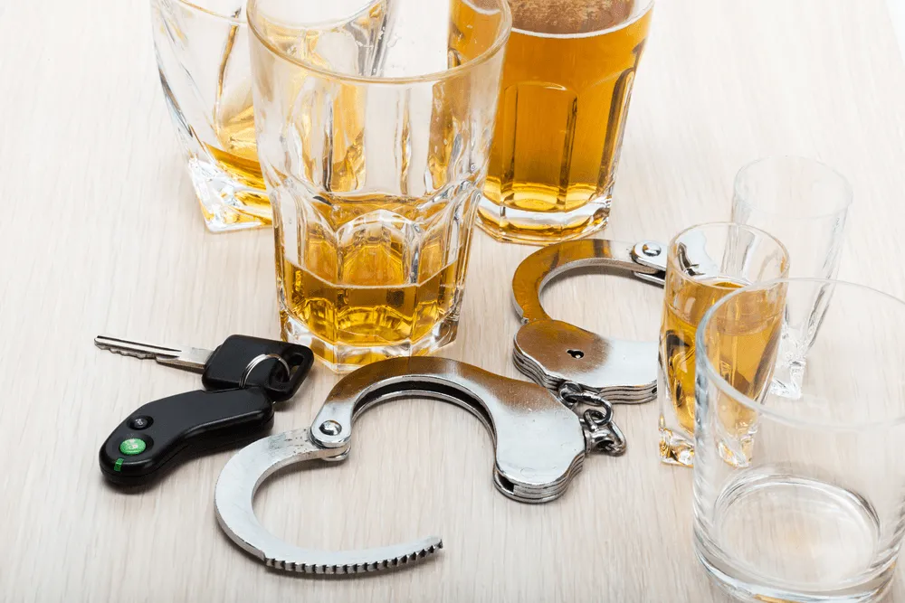 Handcuffs and keys next to many glasses of beer.