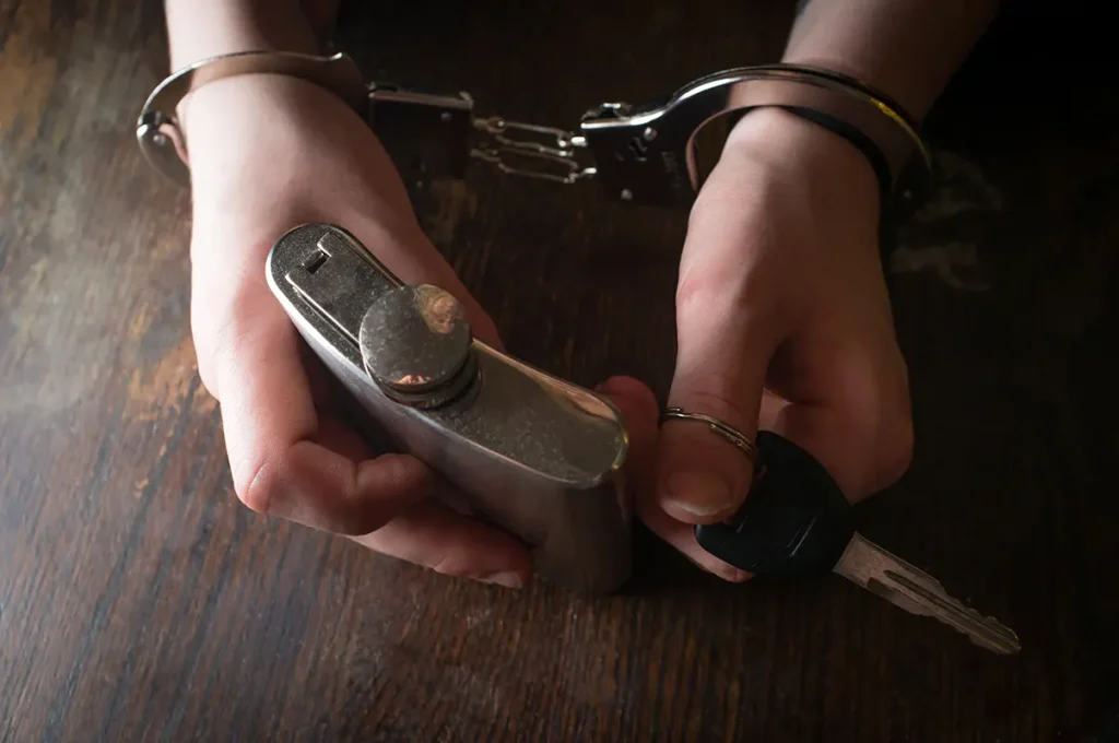 Handcuffed hands holding keys and flask. Contact our DUI defense attorneys today if you’ve been charged with a DUI or DWI in Oklahoma City.