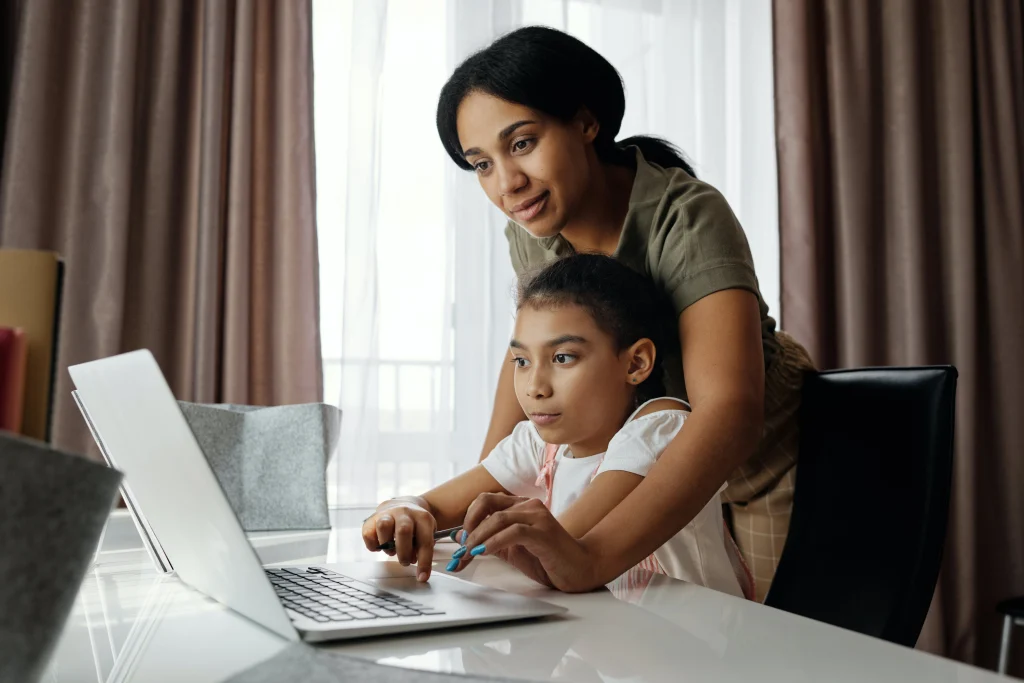 a mother and daughter looking at computer together