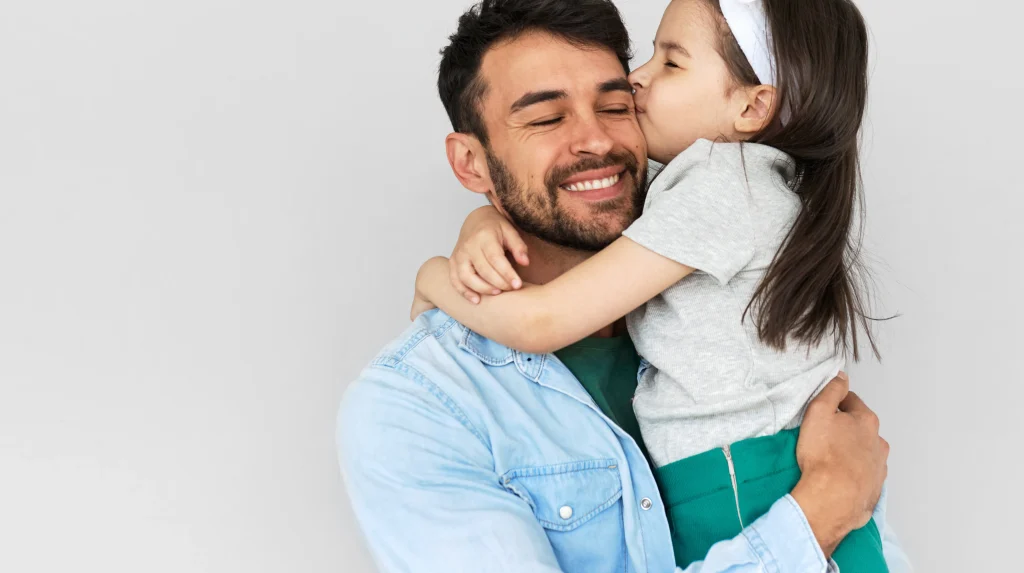 A smiling father holding his daughter.