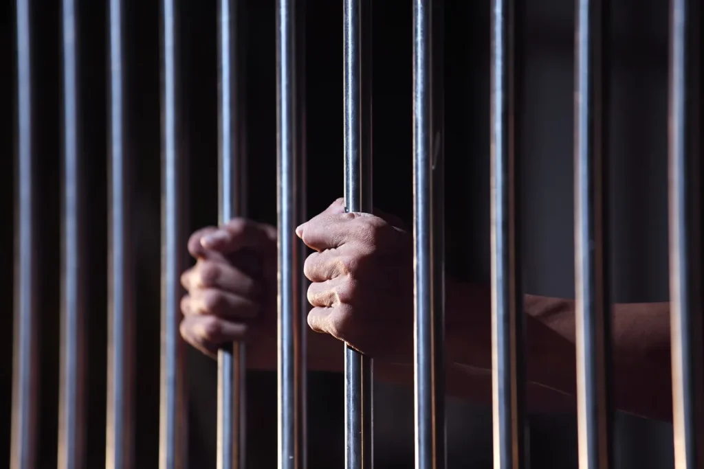 A person holding prison bars.