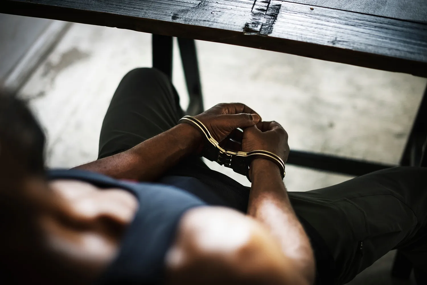 Someone sitting at a table with handcuffs.