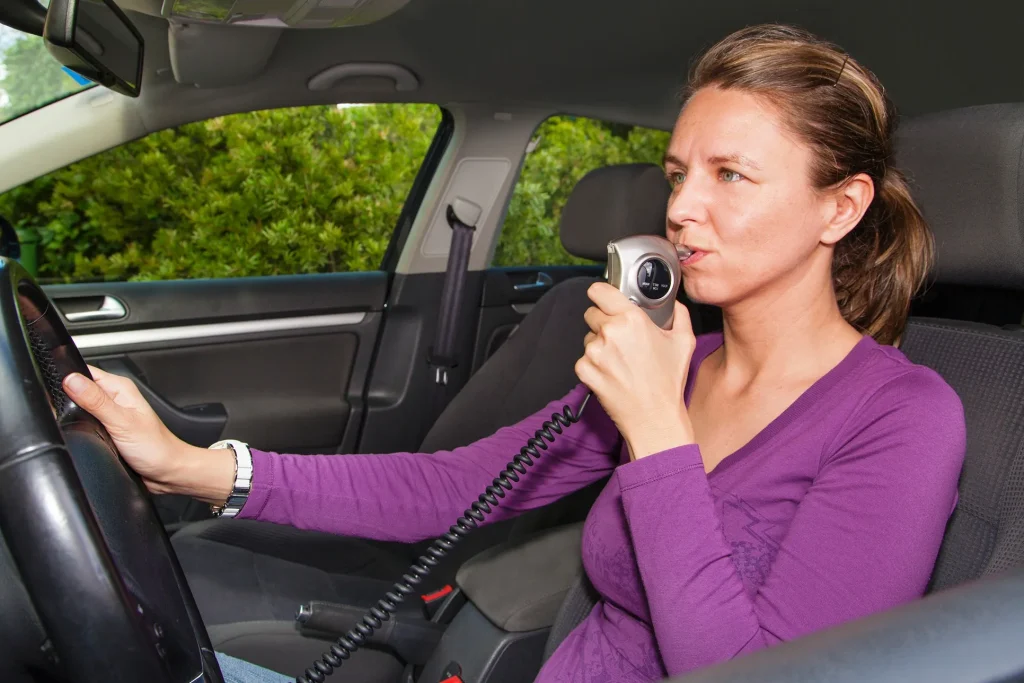 A woman blowing into her ignition interlock device.