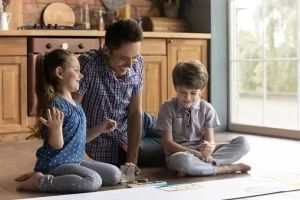A dad playing on the floor with his kids.