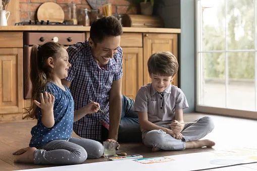 A dad playing on the floor with his kids.