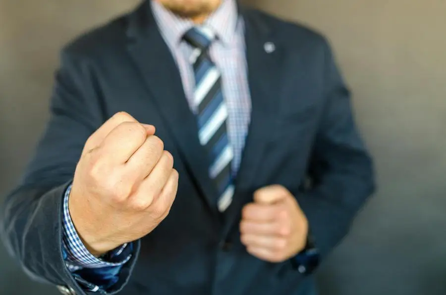 A men in a suit and tie holding up his fist ready to fight