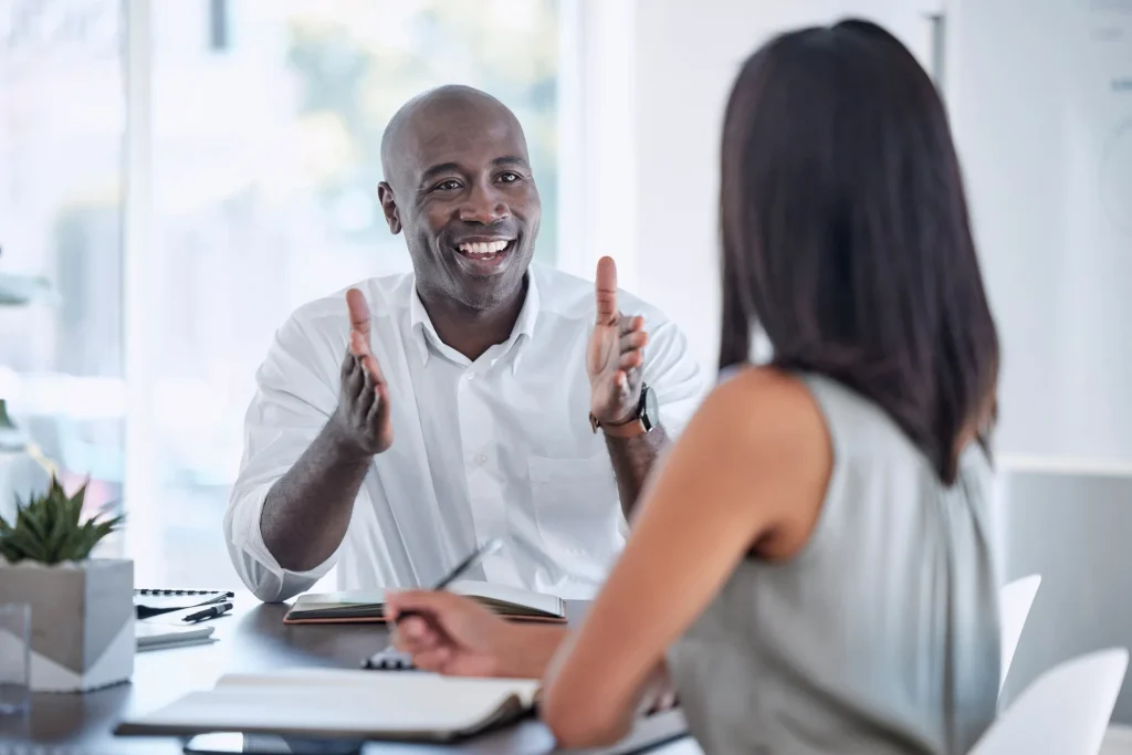 A man animatedly talking to a client in a meeting.
