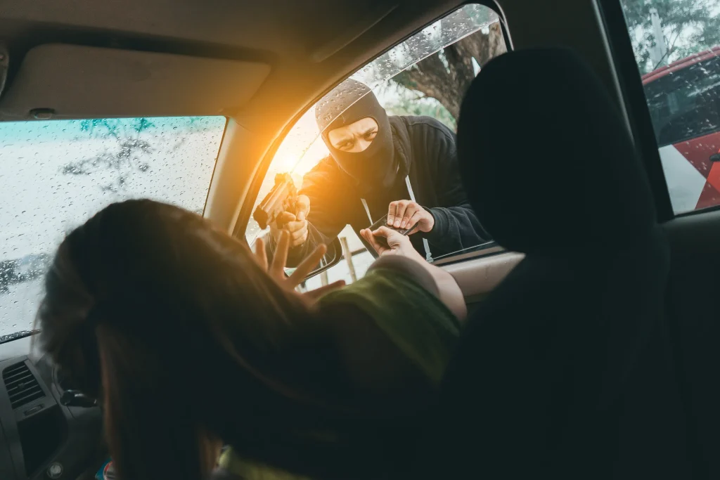 Persona armada cometiendo un asalto e intento de robo a través de la ventana de un automóvil, amenazando al conductor con una pistola.