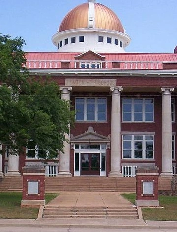 Historic Old Lawton High School building in Lawton, Oklahoma, featuring a red-brick exterior, tall white columns, and a copper-domed roof.