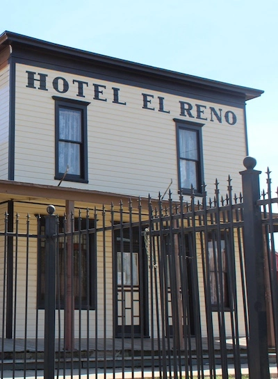 The front of the Hotel El Reno building, surrounded by an old iron fence