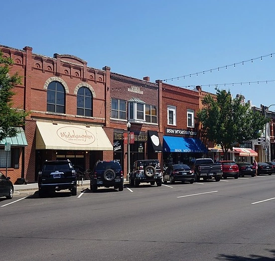 Old historic storefronts in a row with cars parked in front in downtown Norman