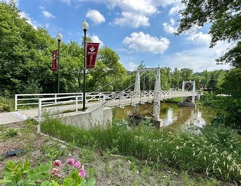 A white bridge that is over a lake with flags on the streetlights