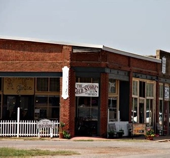 An 'Old store' storefront with a brick building and white picket fence in Piedmont, Oklahoma